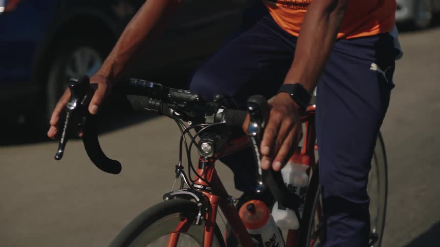 A man rides a bicycle down a street in a residential neighborhood during the day