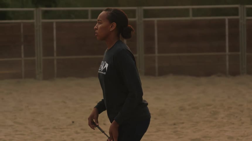 The woman watches the horse run around