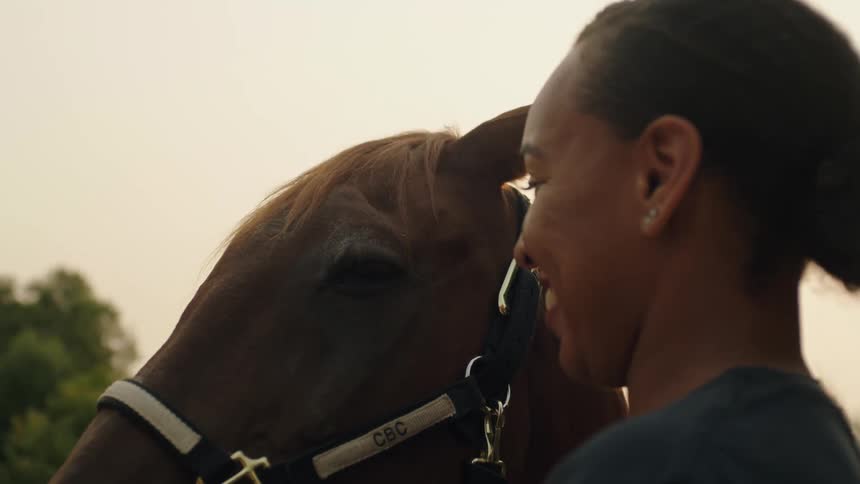 A woman is petting her horse as it tosses its head