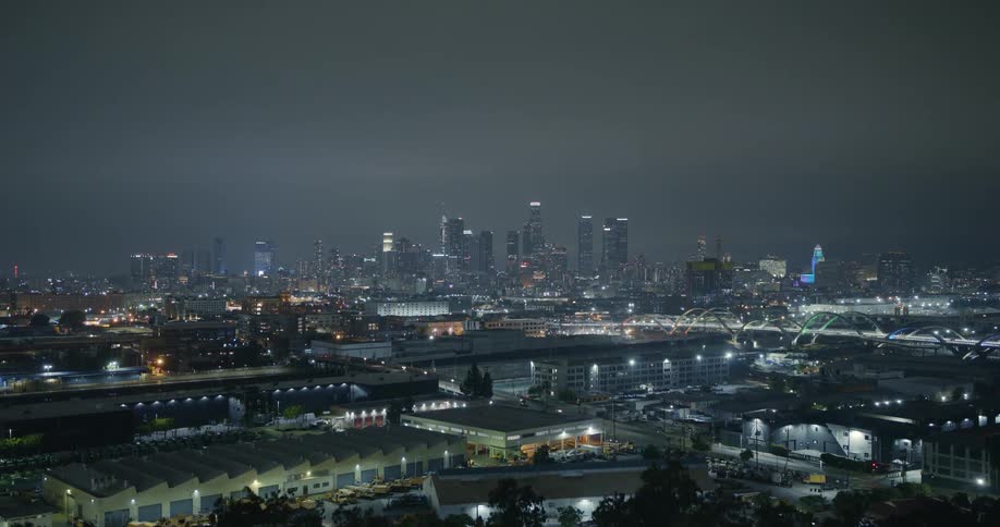 Bridges cross channel between warehouses and downtown during hazy night