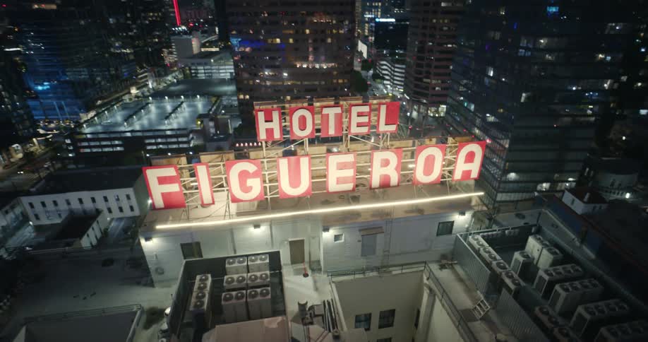 An illuminated sign atop a large building in a metropolis at night