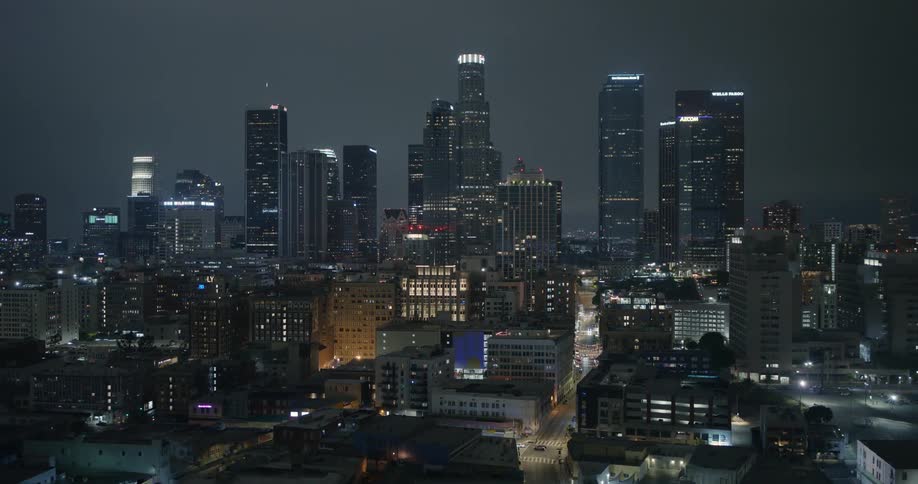 Skyscrapers loom over the smaller buildings in a metropolis at night