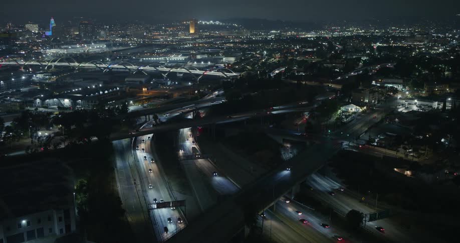 An aerial of a metropolis with busy highway intersections and bridges over waterways