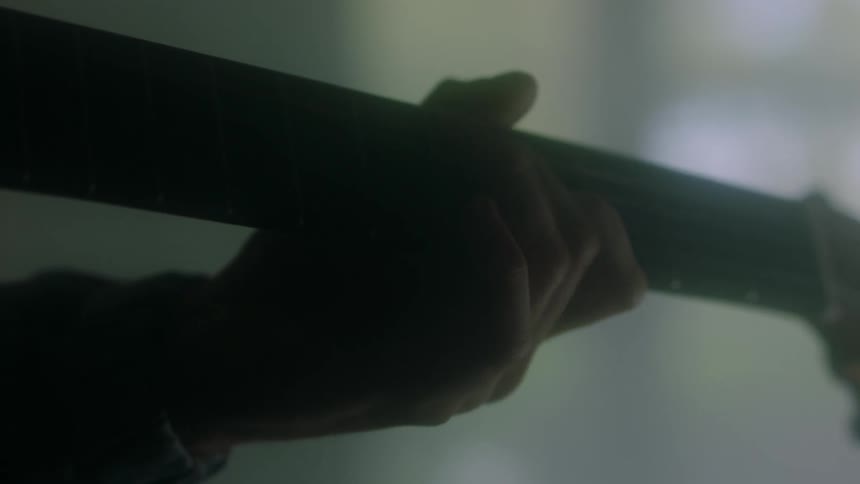 Musician plays guitar in dimly lit room