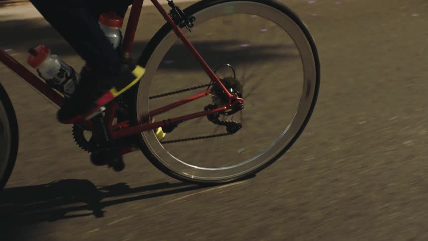 Black man riding a bike on the road next to parked cars