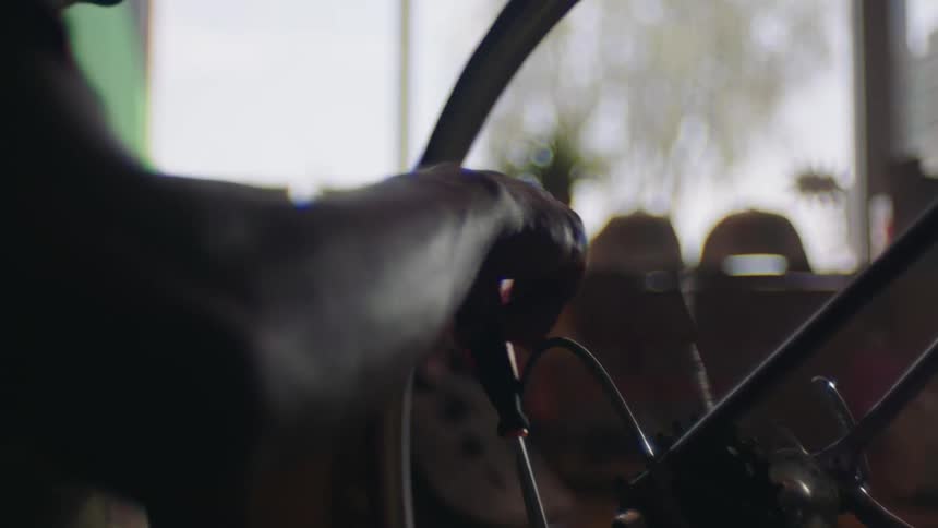 Black man wearing glasses inside a shop fixing a bicycle