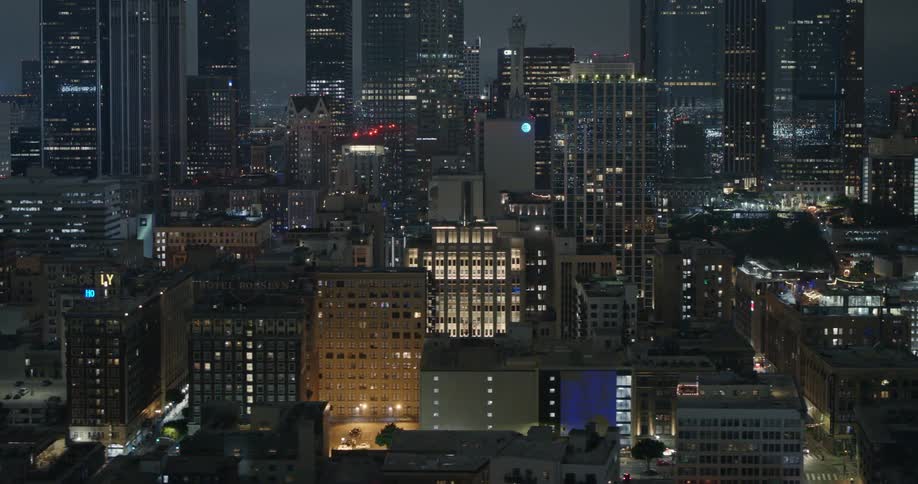 An aerial view of a packed downtown city area filled with skyscrapers lit up at night