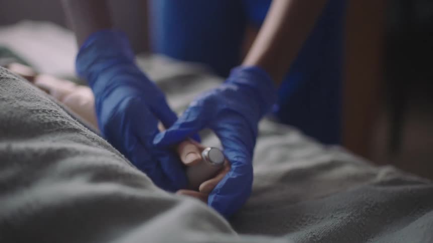 A nurse giving a patient laying on a sick bed a remote