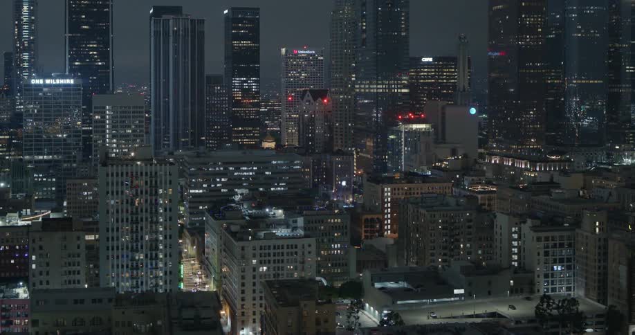 An aerial shot of a litup downtown tower block and skyscrapers lit up at night