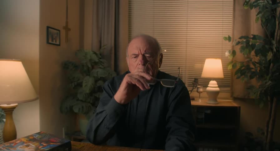 Elderly man in a priests shirt looking stressed before opening a bible