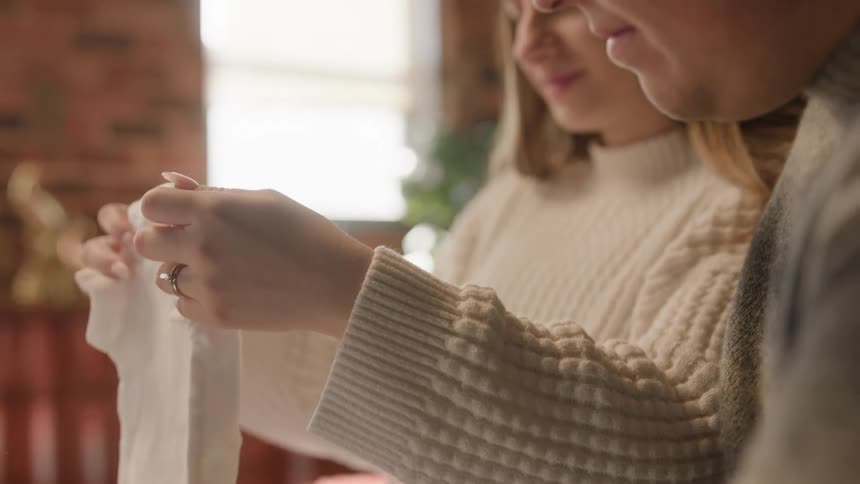 Pregnant woman and her husband sitting down looking at baby clothes