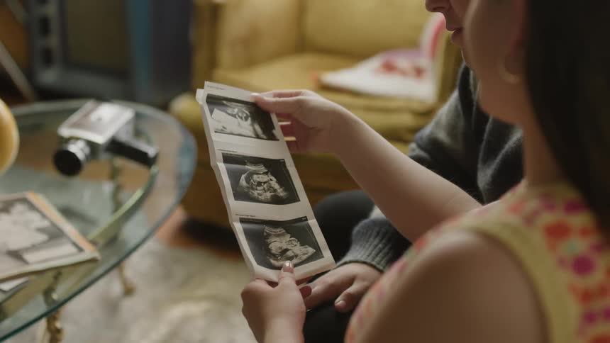 A man and woman sit at home and look at ultrasound pictures