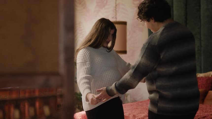 Father and mother stroke pregnant abdomen before slow dancing in bedroom
