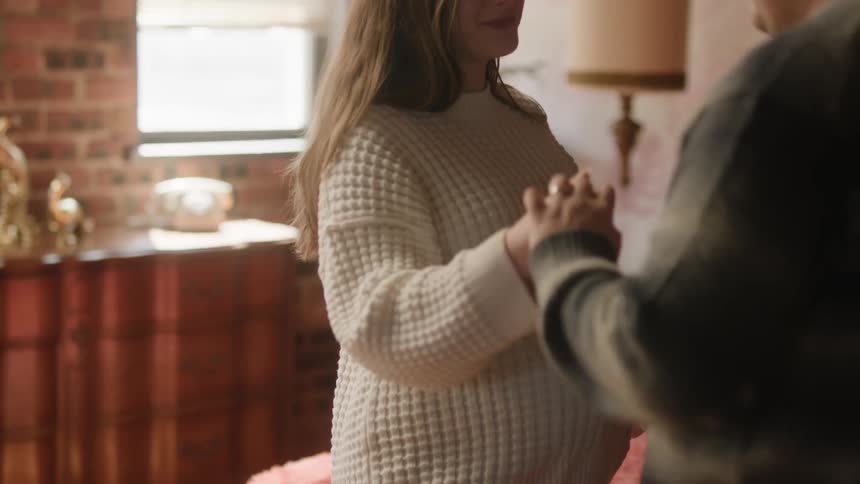 A man slow dances with his pregnant wife