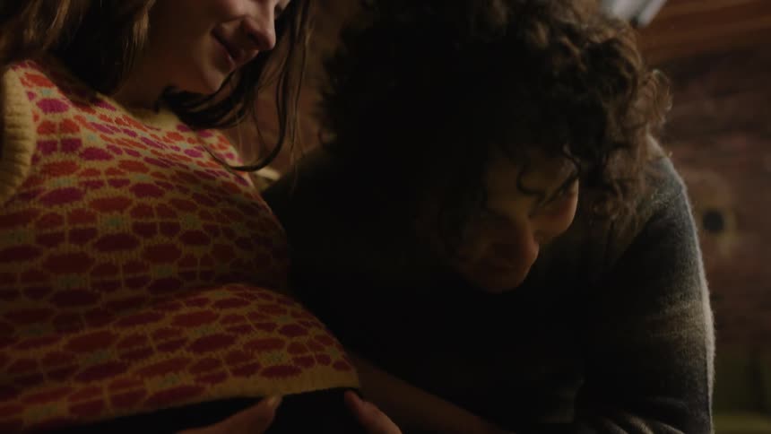 A father puts his head against his pregnant wifes belly