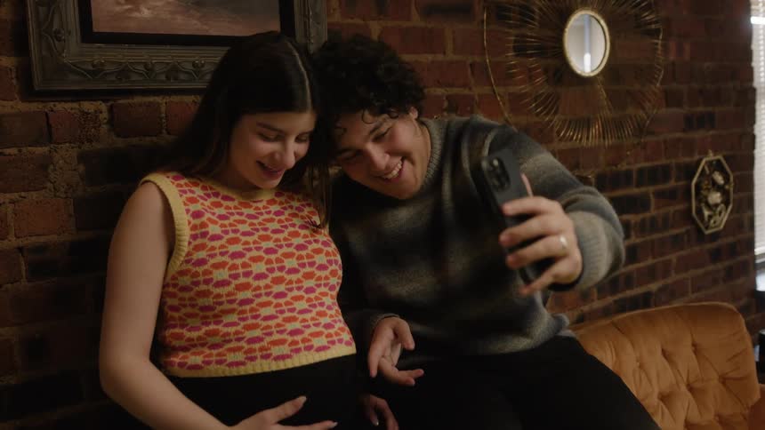 A man and woman take a photo with a cell phone