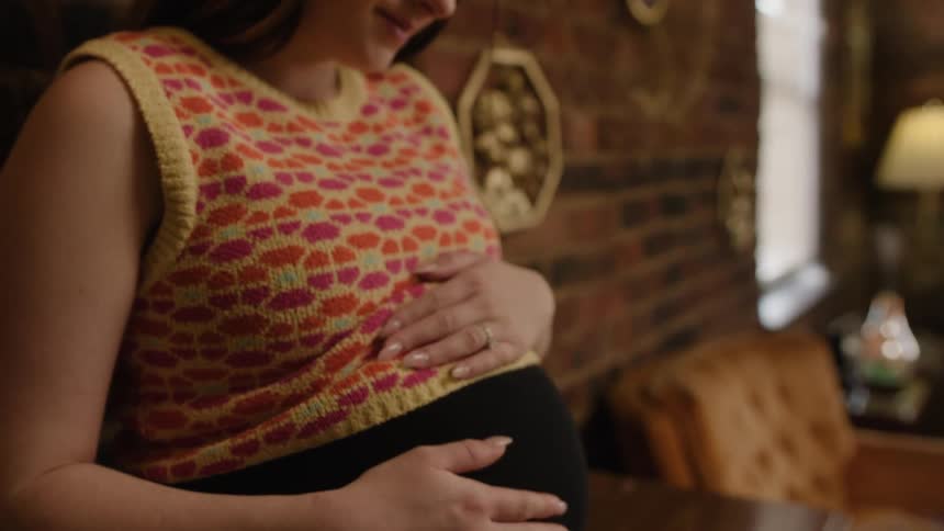 A woman rubs her pregnant belly