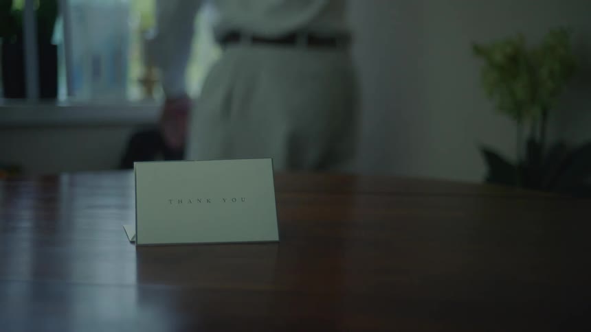 Man places papers in briefcase before turning to table and reading thank you note
