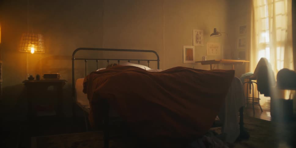 A person sleeping in their bedroom covered with a blanket as daylight streams in through the window