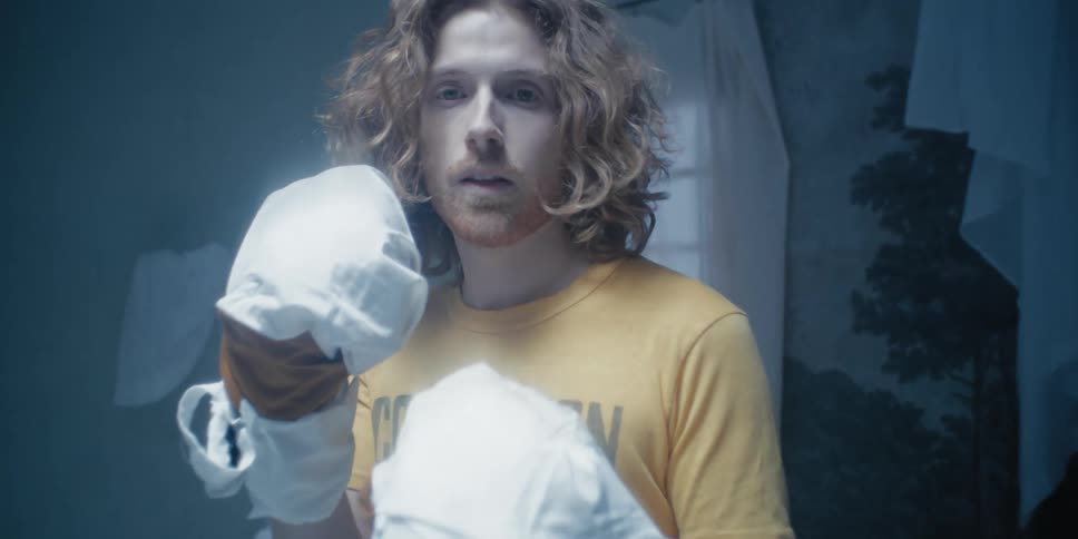 A man is boxing in a room and pretending to be knocked out