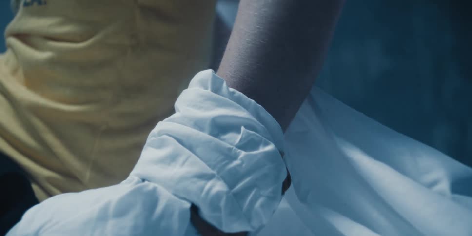 A close up of a mans arm wrapped in a white cloth as he lays down