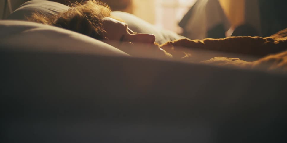 A man is sleeping in his bed during the morning