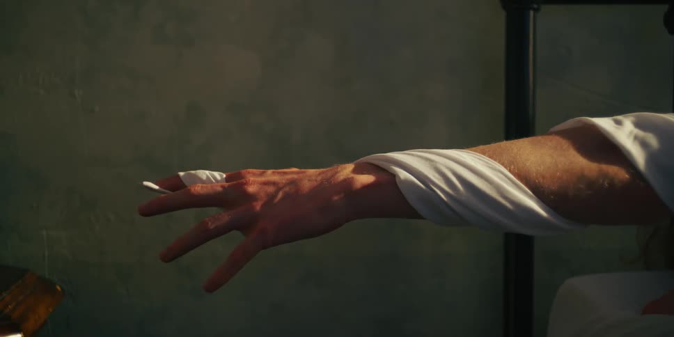 Persons arm outstretched with a white cloth wrapped around it up to the finger as it unravels around the arm and falling