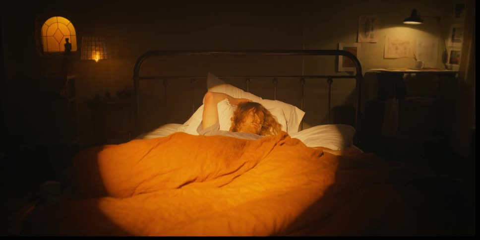 A man is sleeping in bed while the camera zooms dramatically pushing him closer to the wall