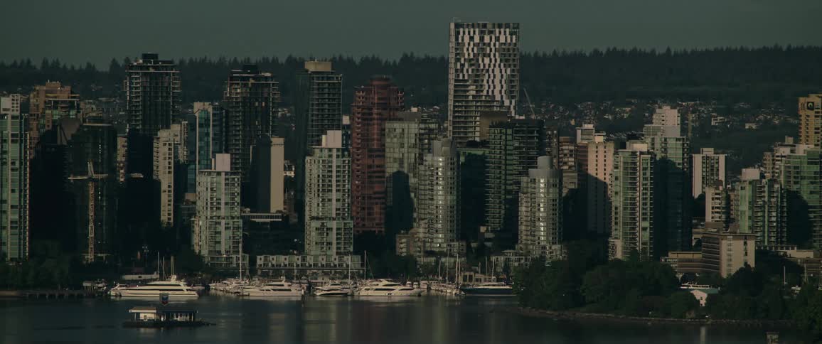 A metropolis on a waters edge with tall buildings aligning the shoreline with boats in the harbor