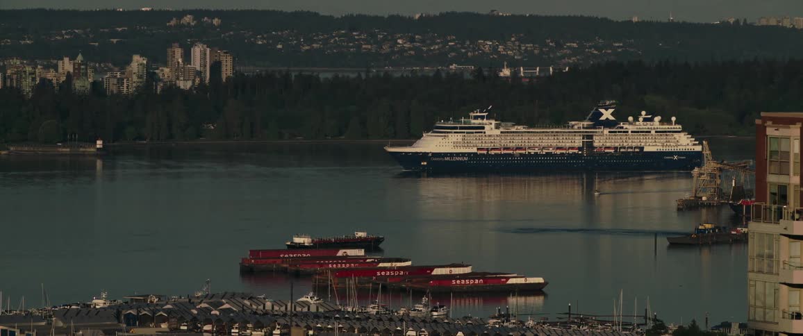 A cruise ship moves slowly through the waters near a big city