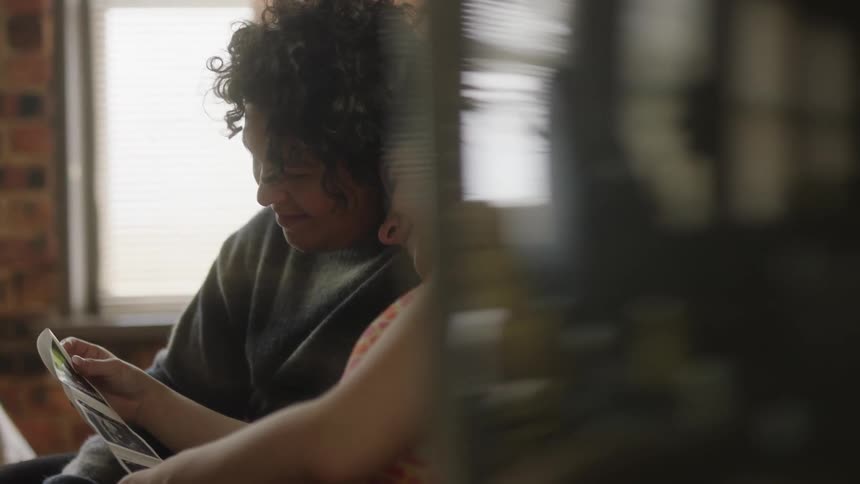 Joyful couple sitting on the couch looking at ultrasound photos