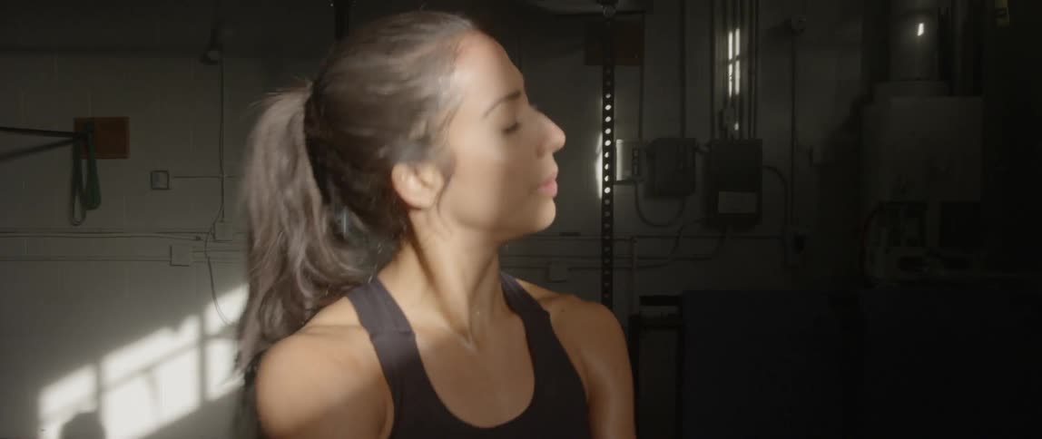 A woman breathes heavily and sweats in a gym