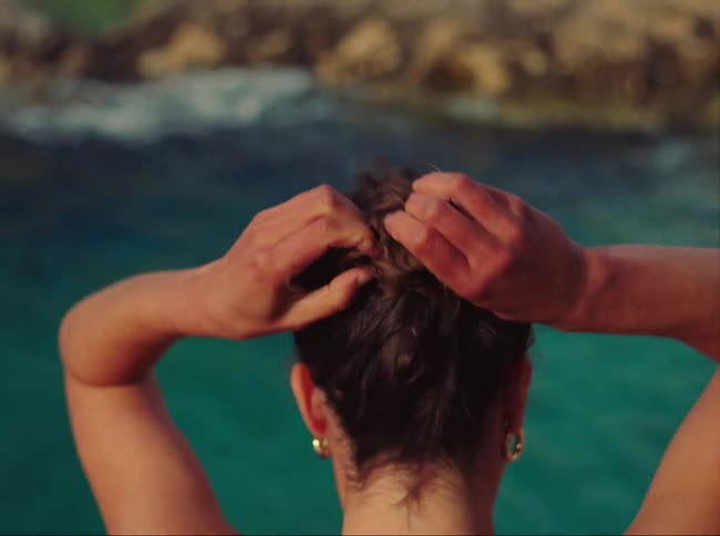Redhead woman preparing her hair and bathing suit before stepping towards to bathe