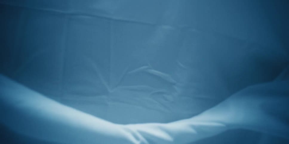White bed sheets on a bed that is standing up right