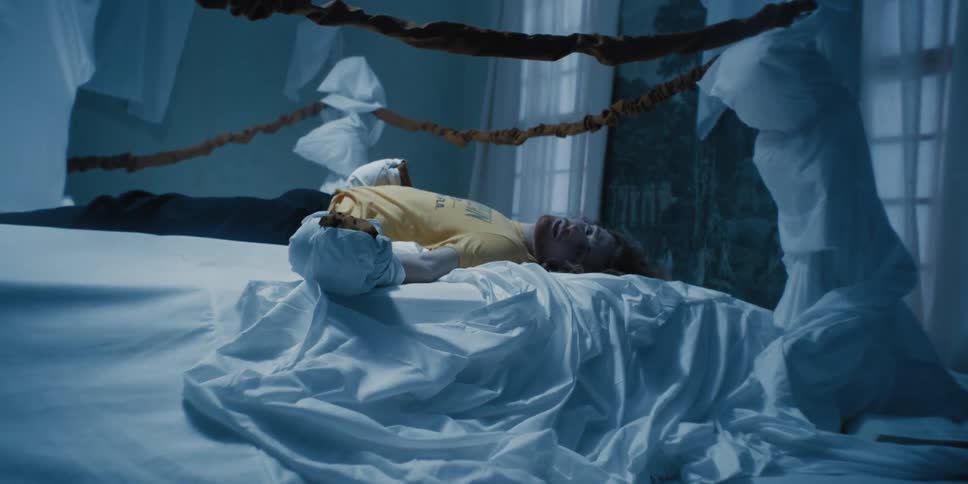 Male performer wearing fabric wrappings on his hands lies in symbolic boxing ring