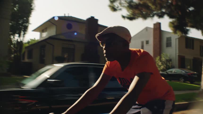 A man rides a bicycle down a street through a neighborhood during the day