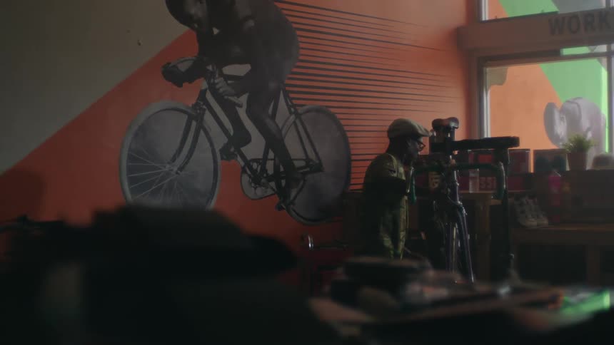 Man works on bicycle in bike shop near fall cyclist mural