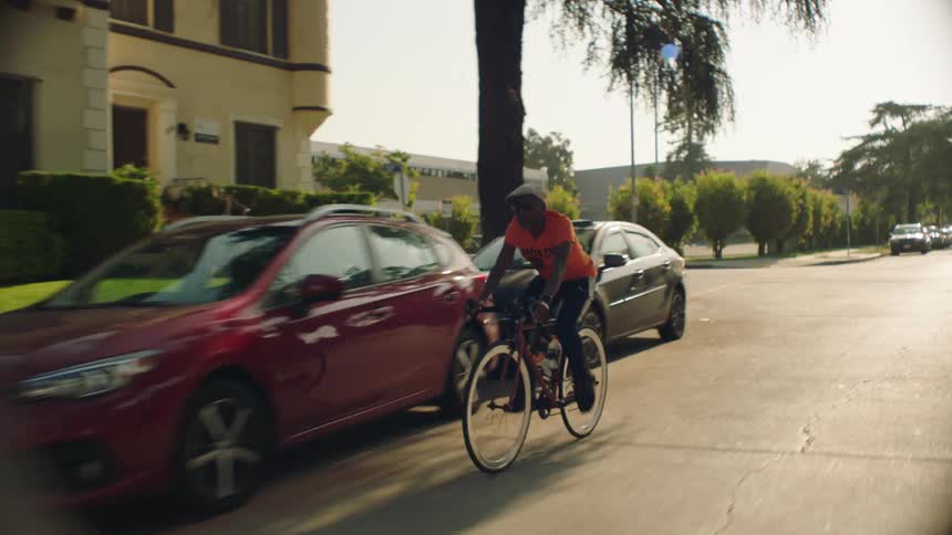A man rides a bicycle down a street in a residential neighborhood during the day