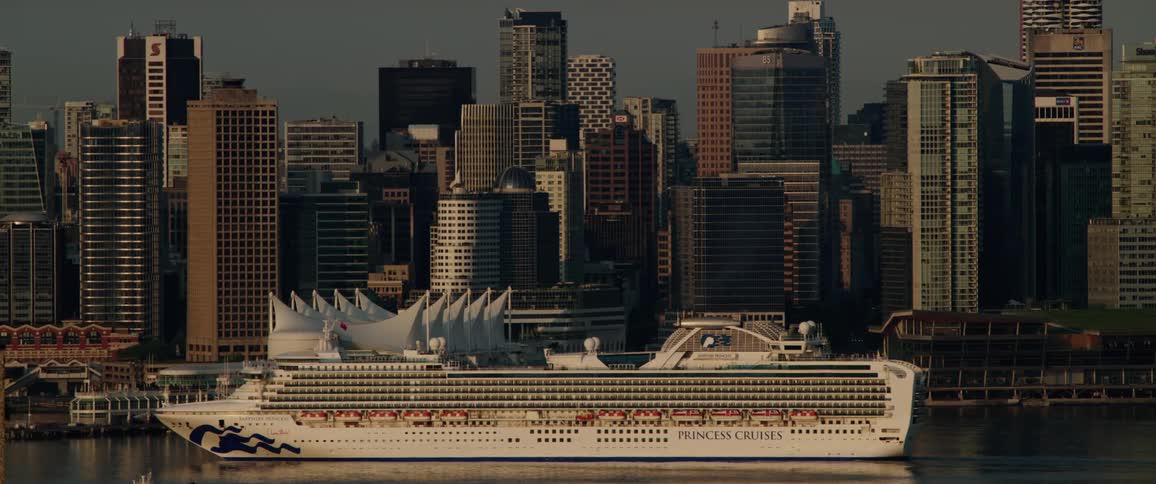 A cruise ship slowly travels along the coast of a metropolis during the day
