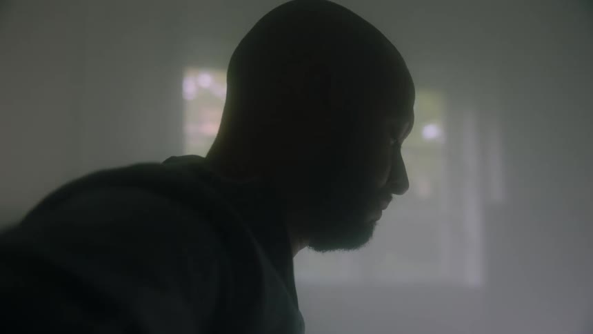 Bearded man sitting down indoors nodding his head in a rhythmic way