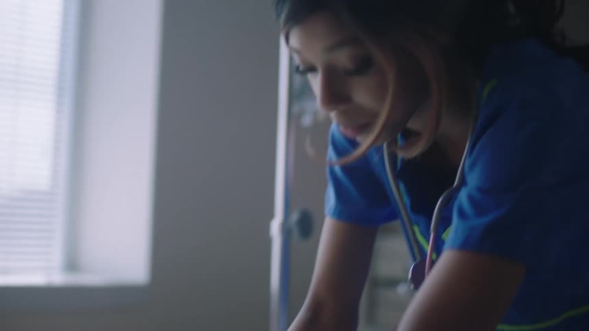 A nurse adjusts a patients bedding while speaking to the doctor