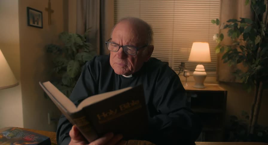 Elderly man sitting reading the bible in his home