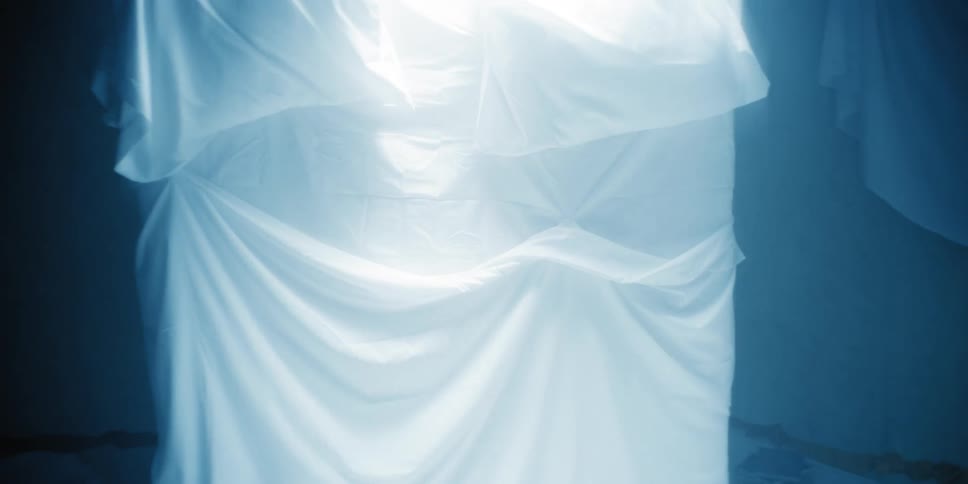 Mattress with white sheets in a dimly lit room