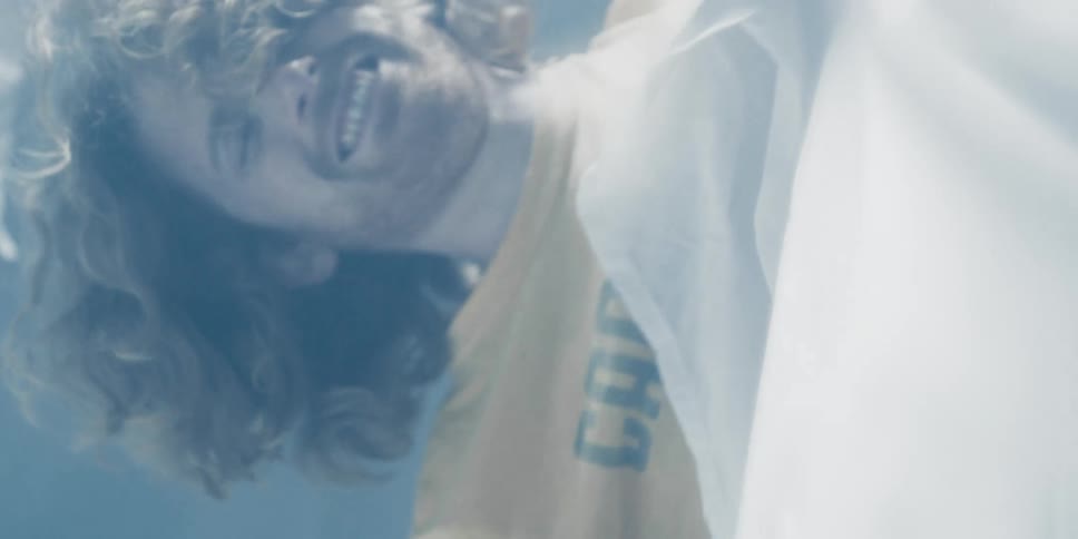 A man winces in pain as his hand is covered with a sheet and tape