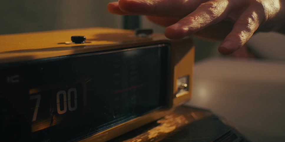 An extreme close up of a persons hand on an alarm clock on a table