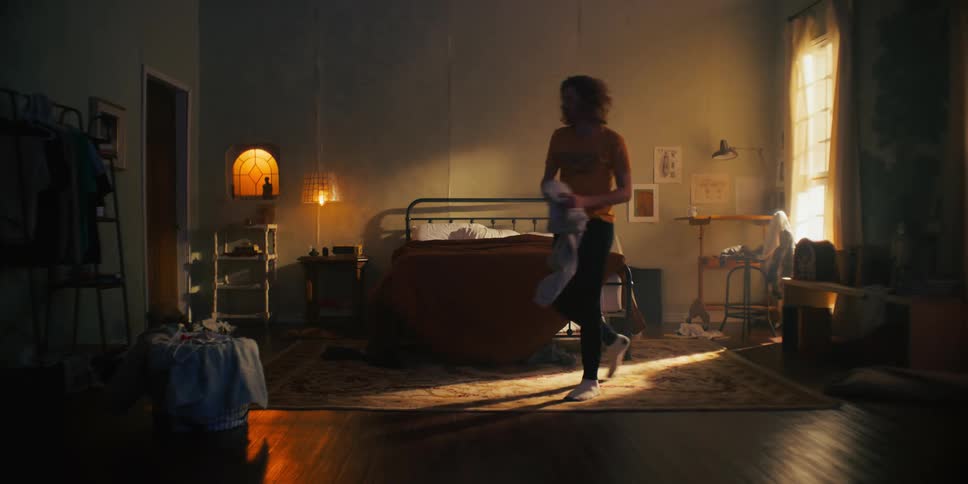 A man throws clothing around his bedroom