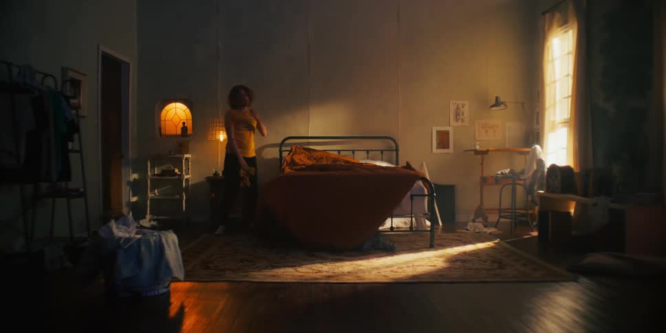 Light shines into shadowed bedroom as man picks up his room