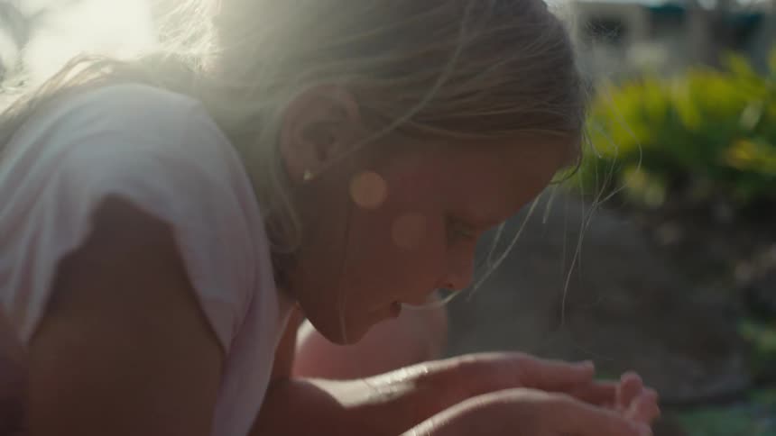 A young girl looking at pond water cupped in her hands