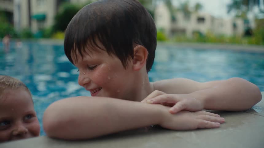 Two joyful kids having fun in the hotel pool on a sunny day