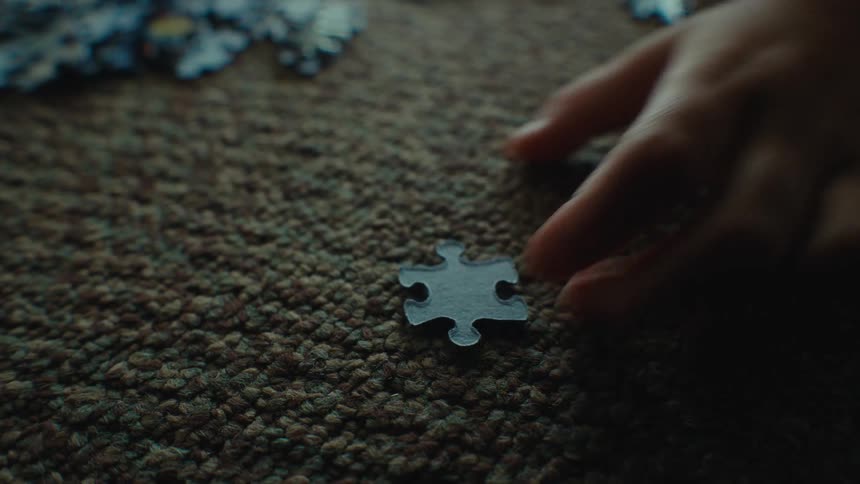 A puzzle piece is picked up by a childs hand